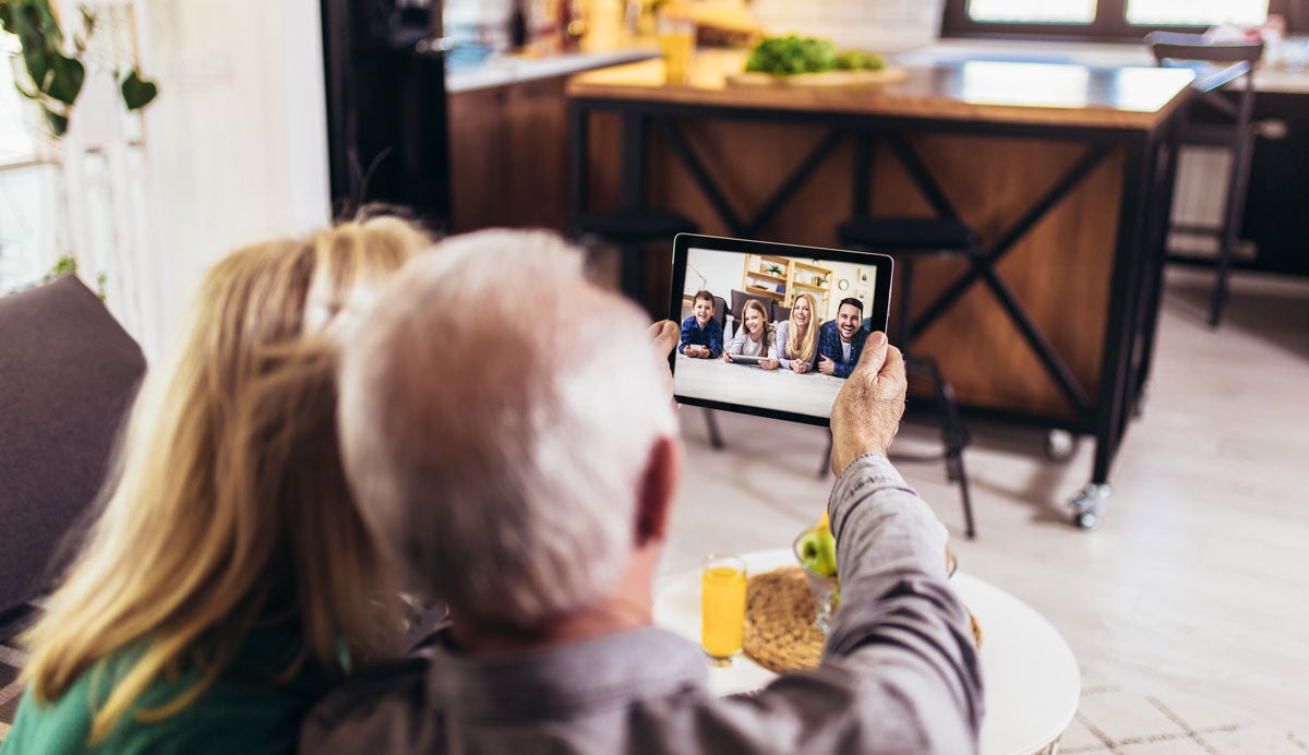 Older man looks at device screen, for online gathering.