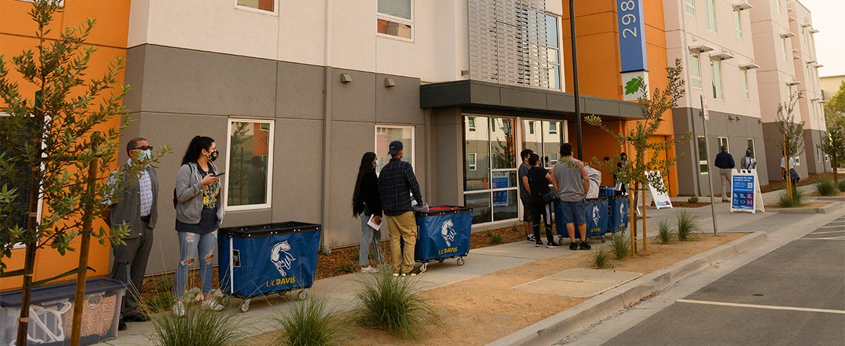 Students and parents with carts wait to move in.