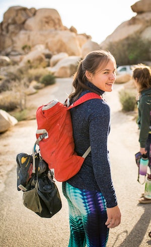 Ula is hiking in a desert area with a backpack and is turning around. 