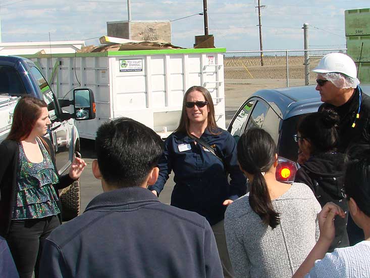 Woman addresses a crowd of students with a man in a hard hat listening