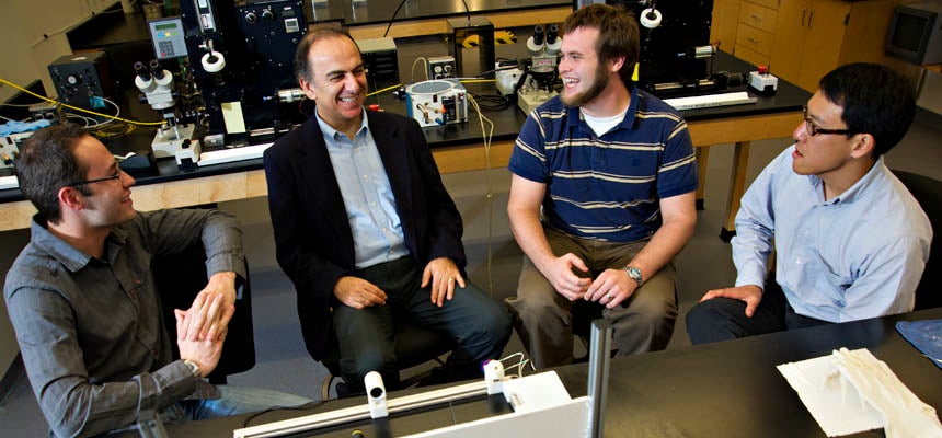 directors of the TEAM lab sit with two male students in the lab