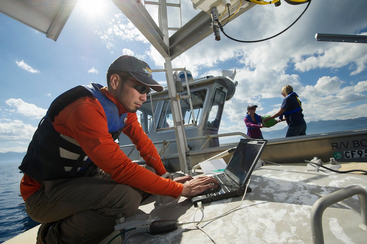 Shohei Watanabe crouches over computer on a boat at Lake Tahoe