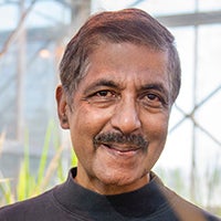 Face of a smiling man with brown skin, dark hair and a mustache. 