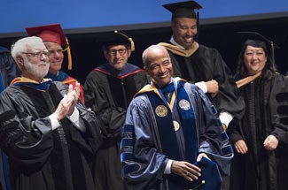 Chancellor May in academic regalia, wearing medal, smiling, at investitureat in
