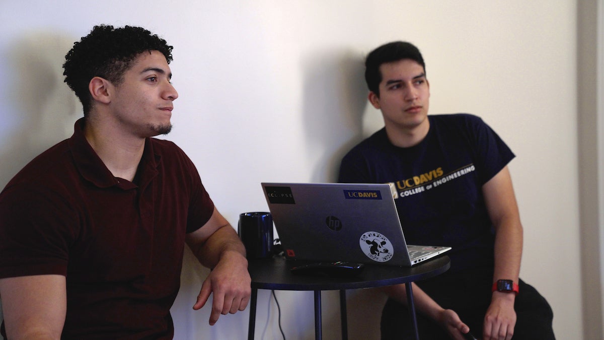 Two male engineers from UC Davis sit in chairs with laptop between them