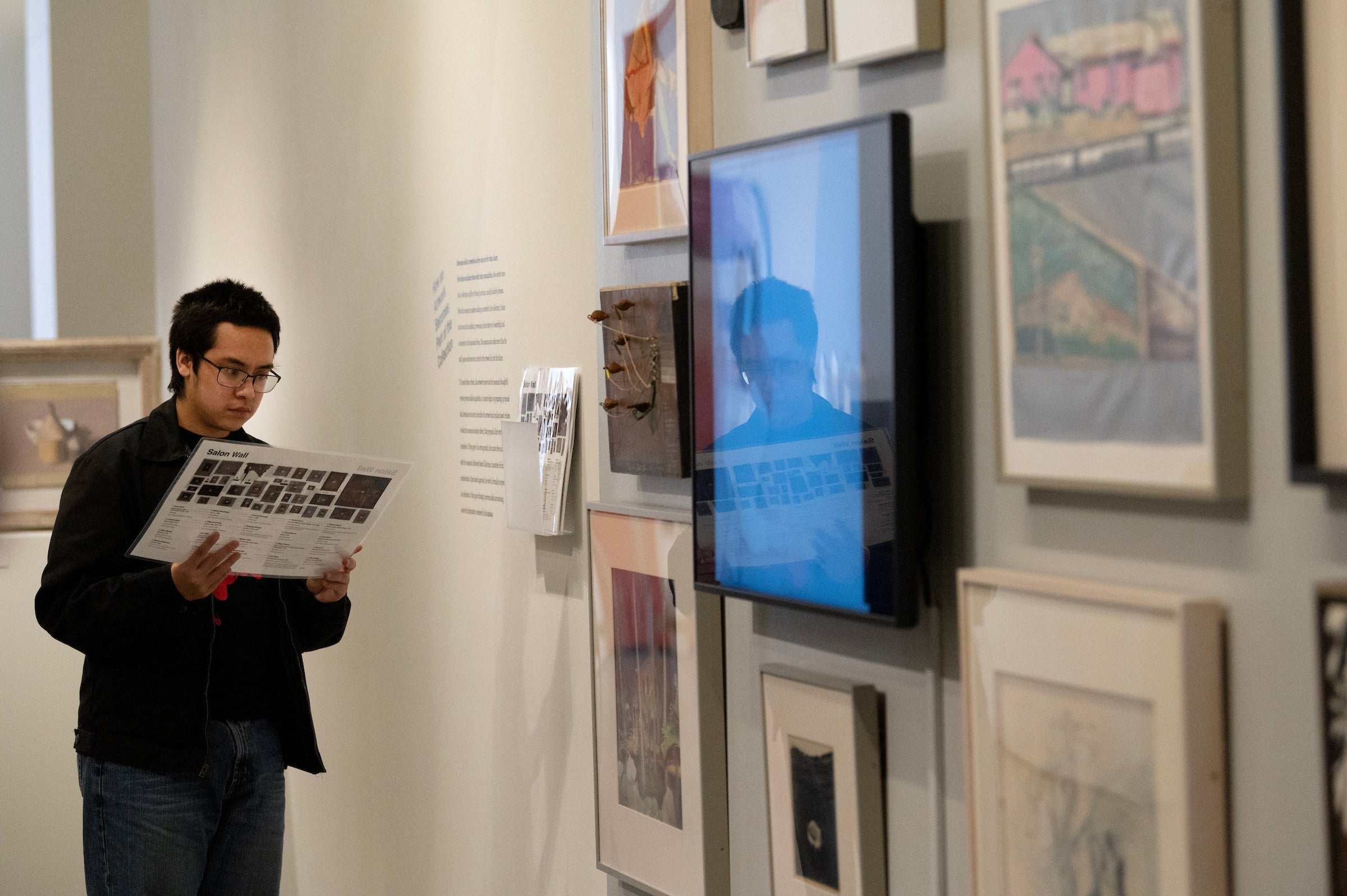 Cadmeal Tapiz Zapata, a junior Art History student, illustrates how museum visitors can identify art and artists on the Salon Wall. The wall includes a an art video as well. 
