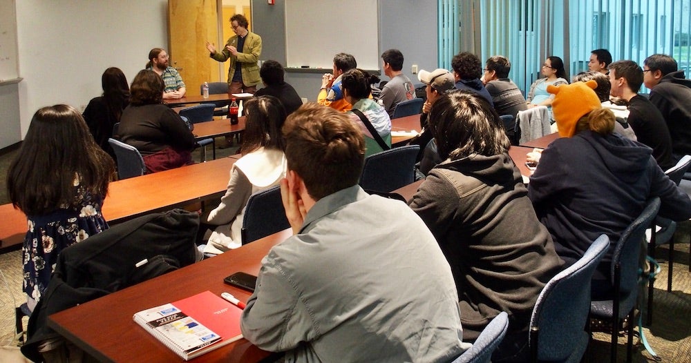 Professor Foster stands in front of a class with a guest presenter at UC Davis. 