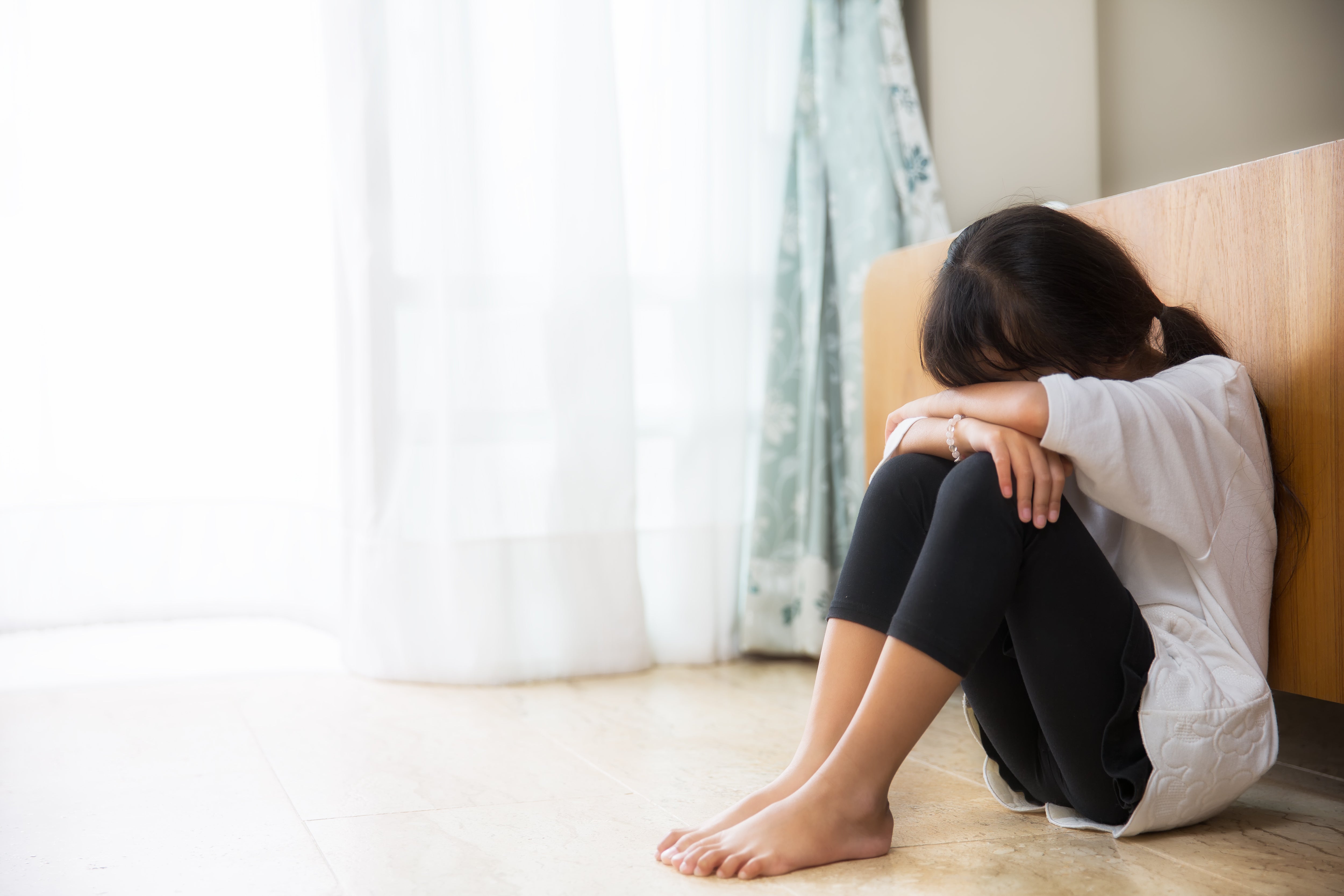 Childhood trauma increases the risk of health professions students developing mental health issues. The UC Davis School of Medicine, the Betty Irene Moore School of Nursing at UC Davis and the UC Davis School of Veterinary Medicine have programs in place to assist students through their long and rigorous academic journeys. Here a woman is shown at the end of her bed sitting on the floor with her head down.