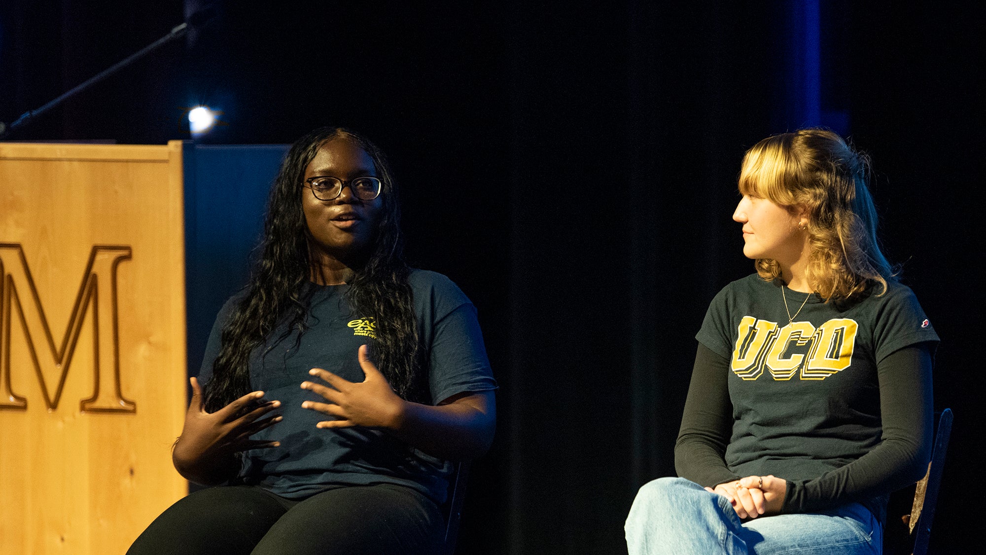 Two seated women, one talking and one listening