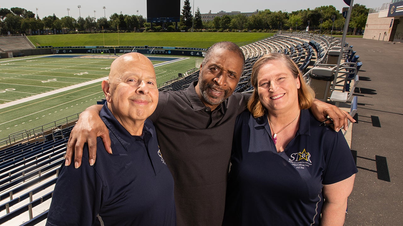 Ron Austin is flanked by Mike Valenzuela and Tracy Grissom with the UC Davis Health Stadium field in the background 