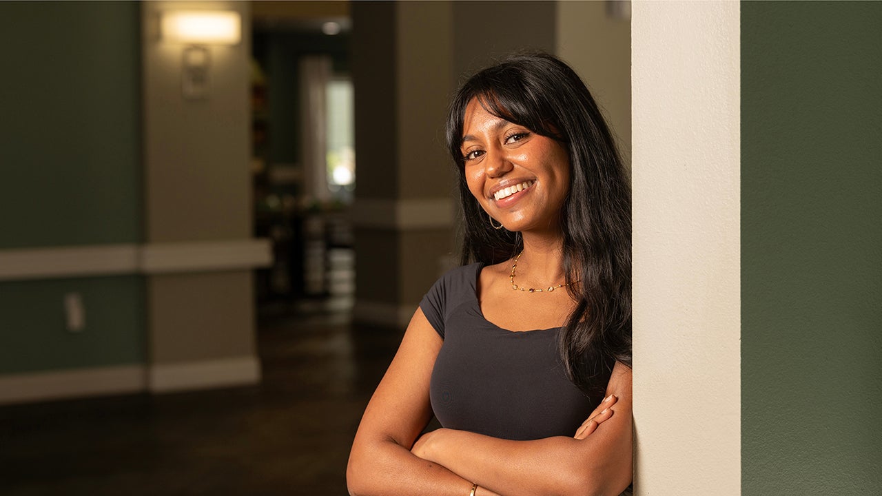 Closeup of Avantika Gokulnatha, arms crossed, leaning against a wall