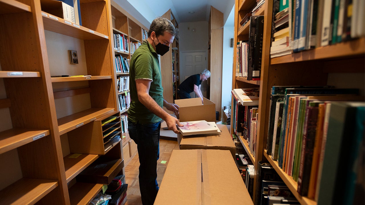 Two men and cardboard boxes among bookshelves