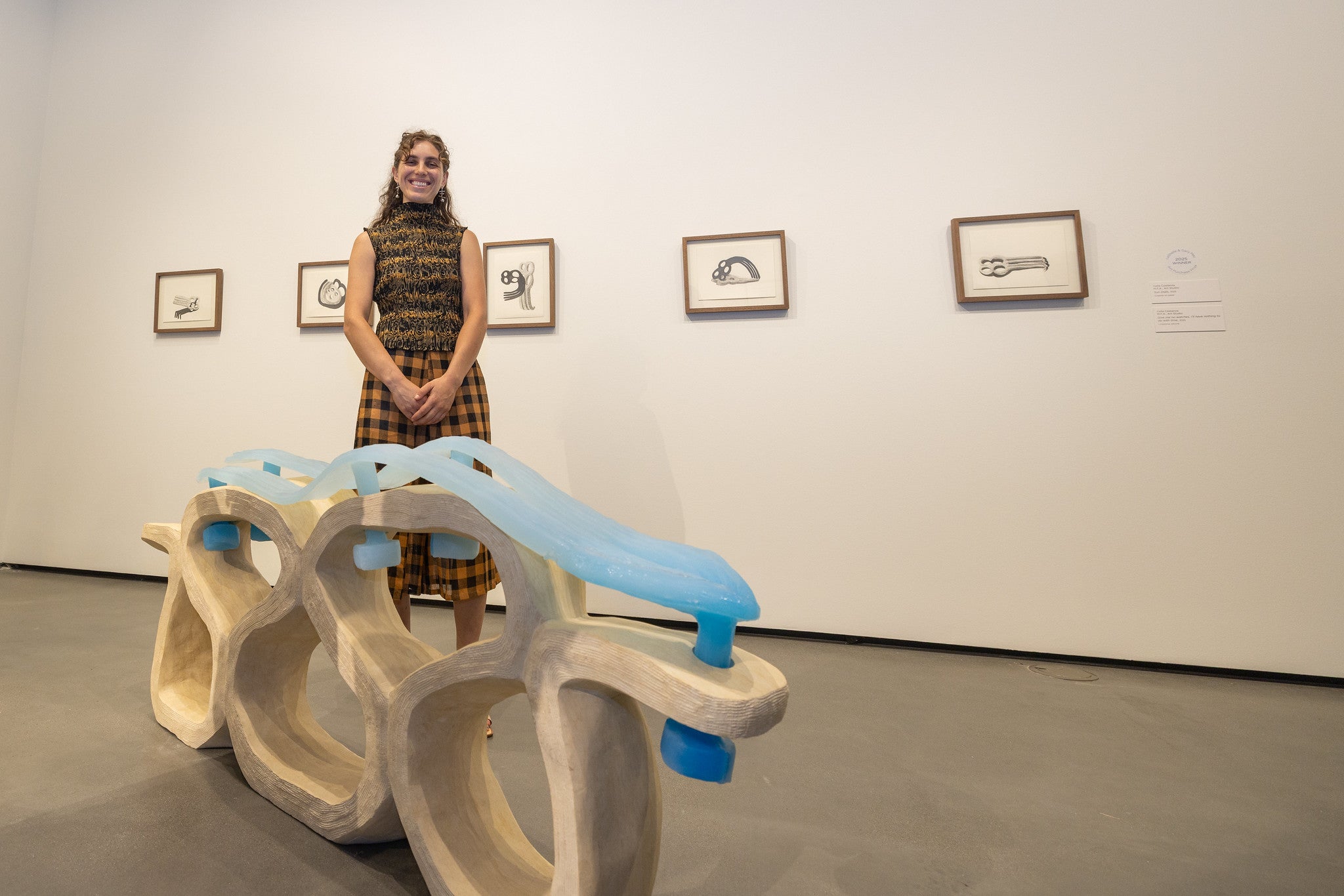 Woman near white wall with multi-colored sculpture in foreground