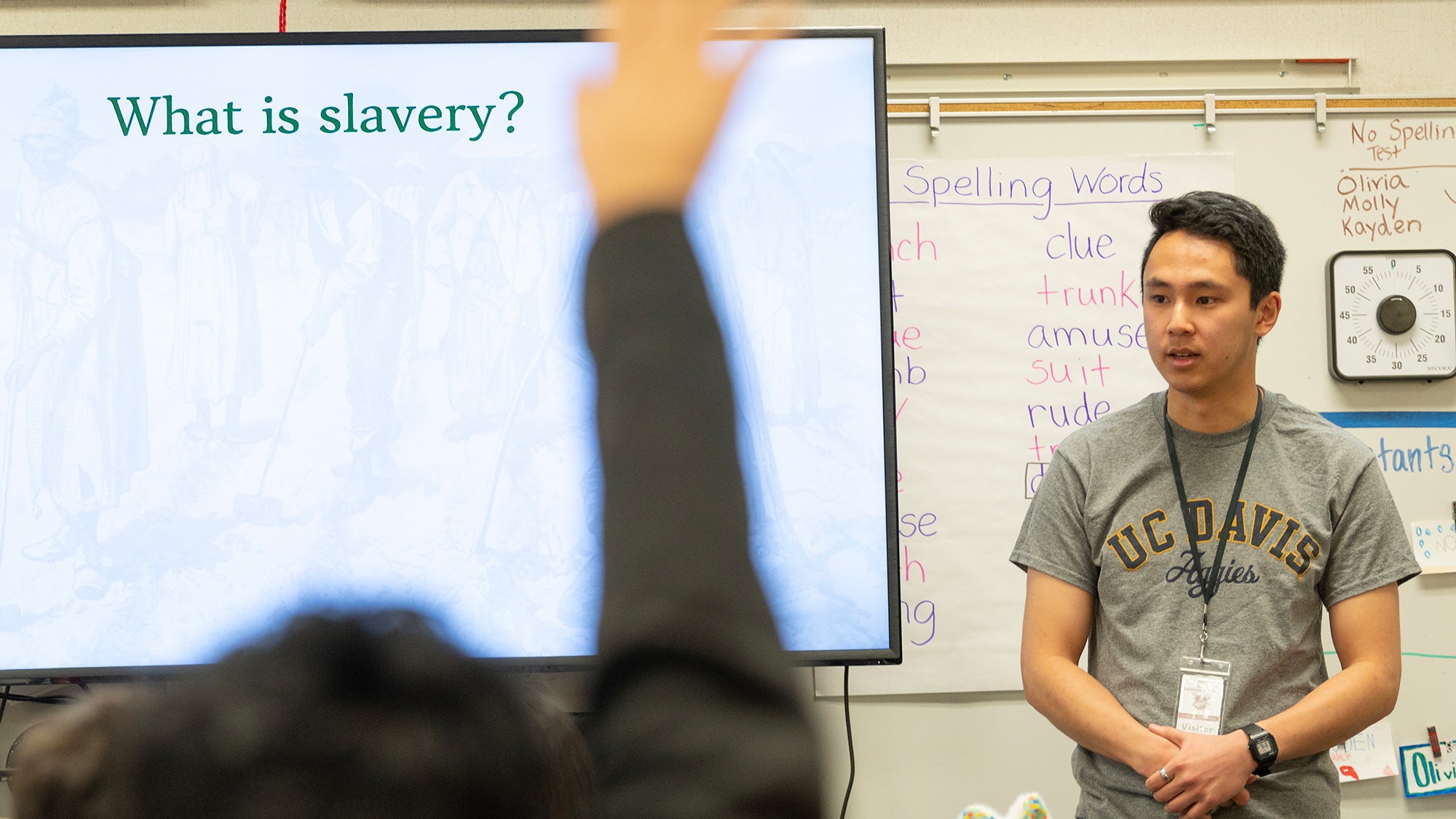 A college student takes questions in an elementary school classroom.