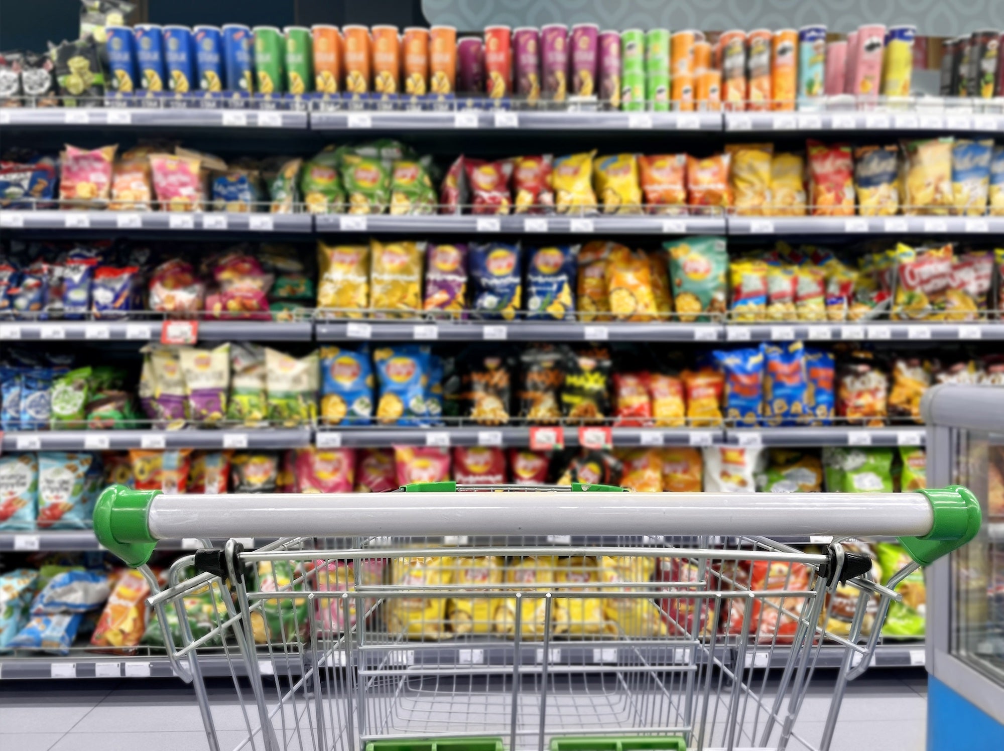 A grocery cart view of a shelves stocked with bags of colorful chips and snacks. Processed food is everywhere and chances are you're eating more of it than you think. (Getty)