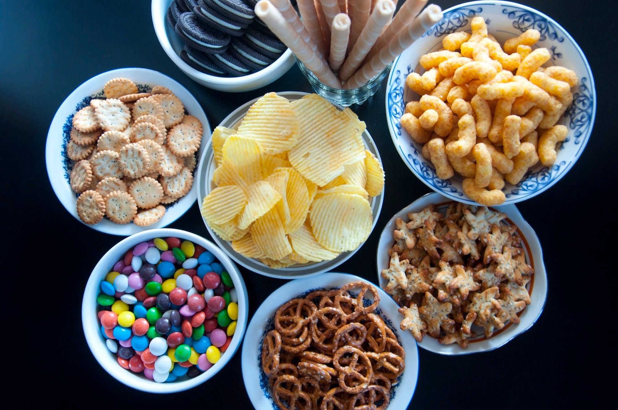 In this episode of Unfold, we uncover the science and debate behind processed and ultra-processed foods. Shown here are eight bowls with various processed and ultra-processed foods, including chips, pretzels and candies.(Getty)