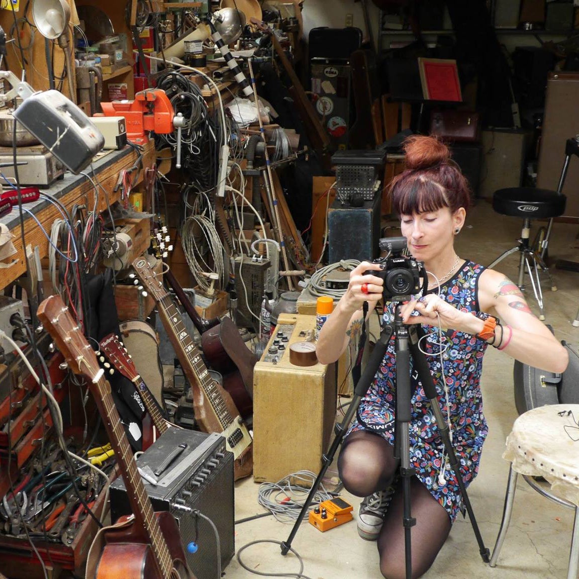 A woman kneels amongst a lot of recording equipment and instruments