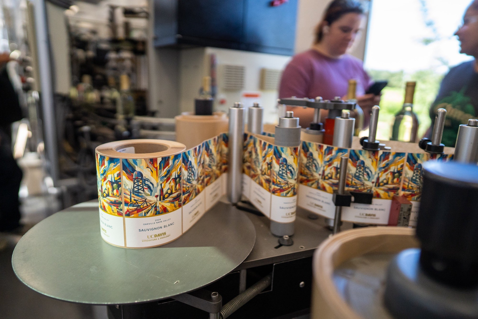 Multicolored labels of the Oakville Station sauvignon blanc are fed from a spool into a machine that affixes them to bottles. (Jael Mackendorf / UC Davis)