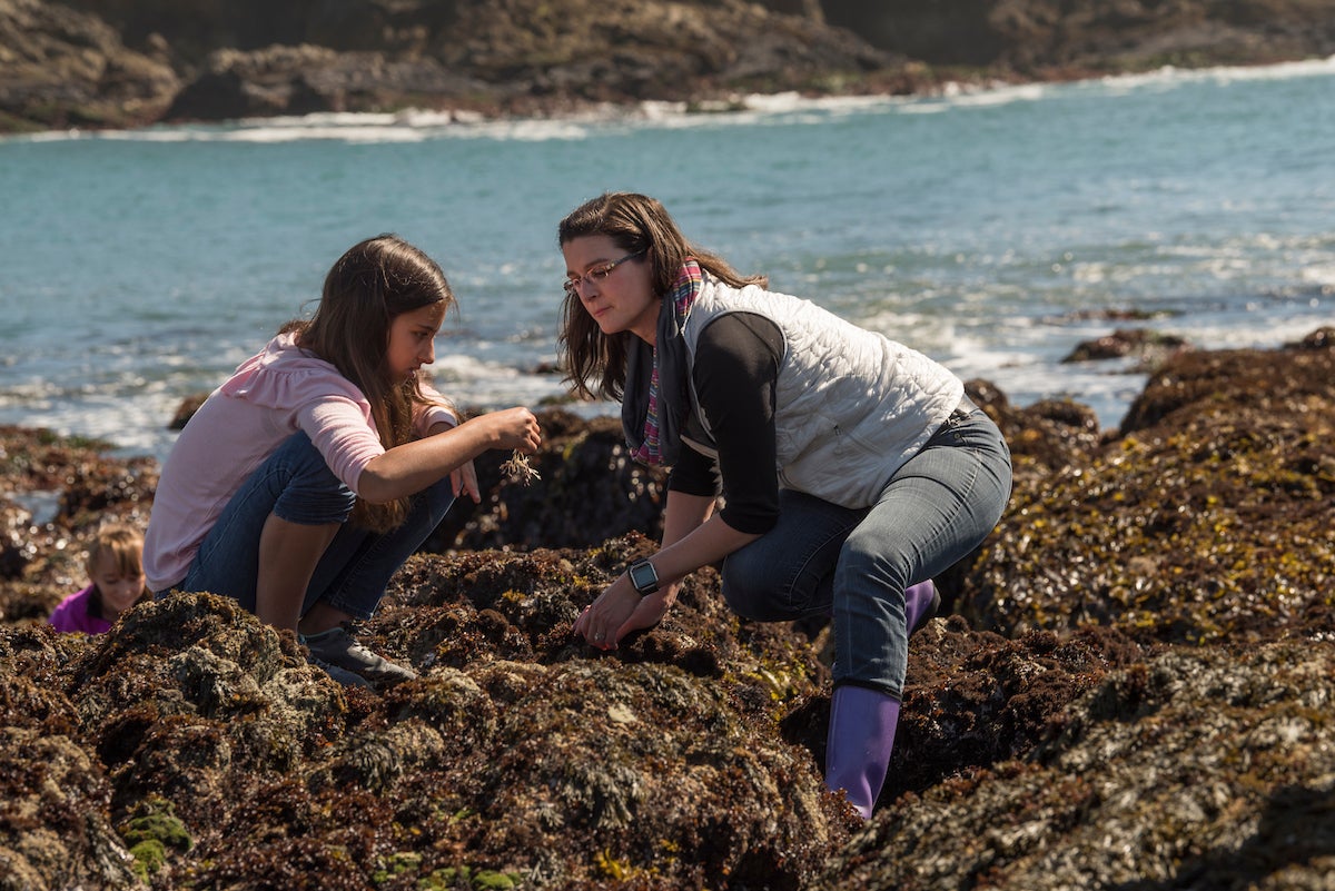 Young girl and Tessa Hill explore tidelpools with ocean in background
