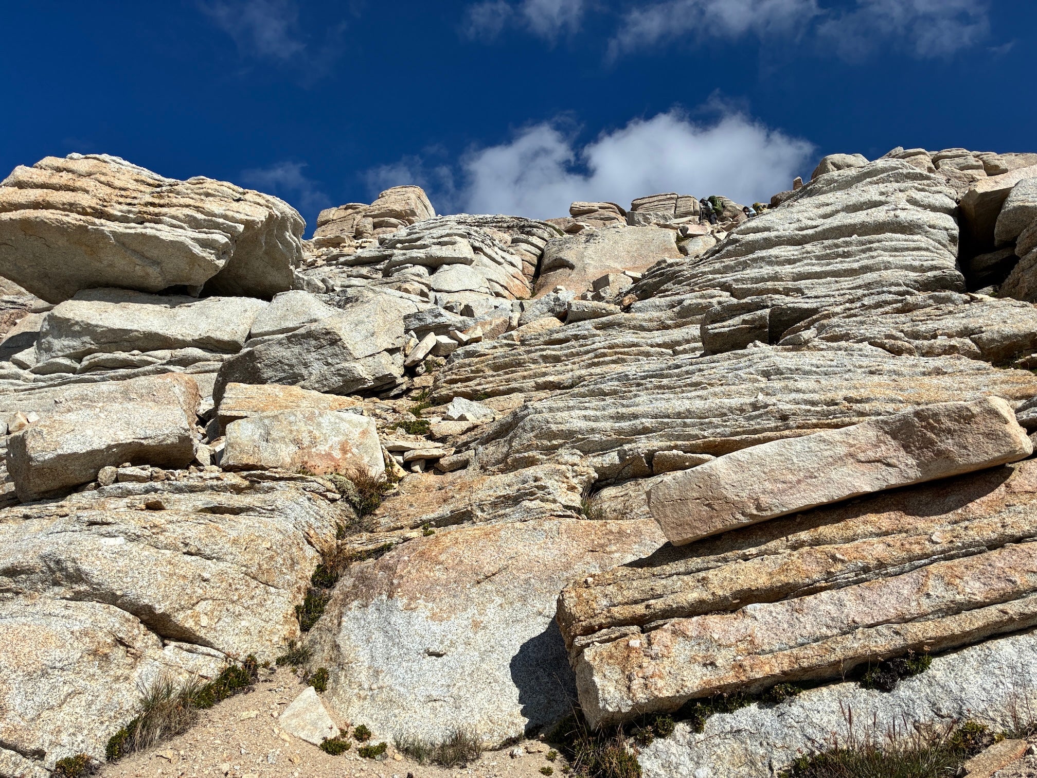 stacks of granite reach to blue sky. A hiker is near the top, indicating a trail among the rocks. 