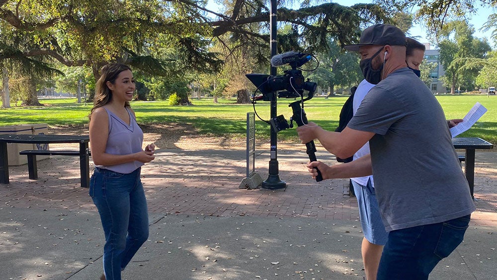 A woman walks toward a cameraman as she is being filmed
