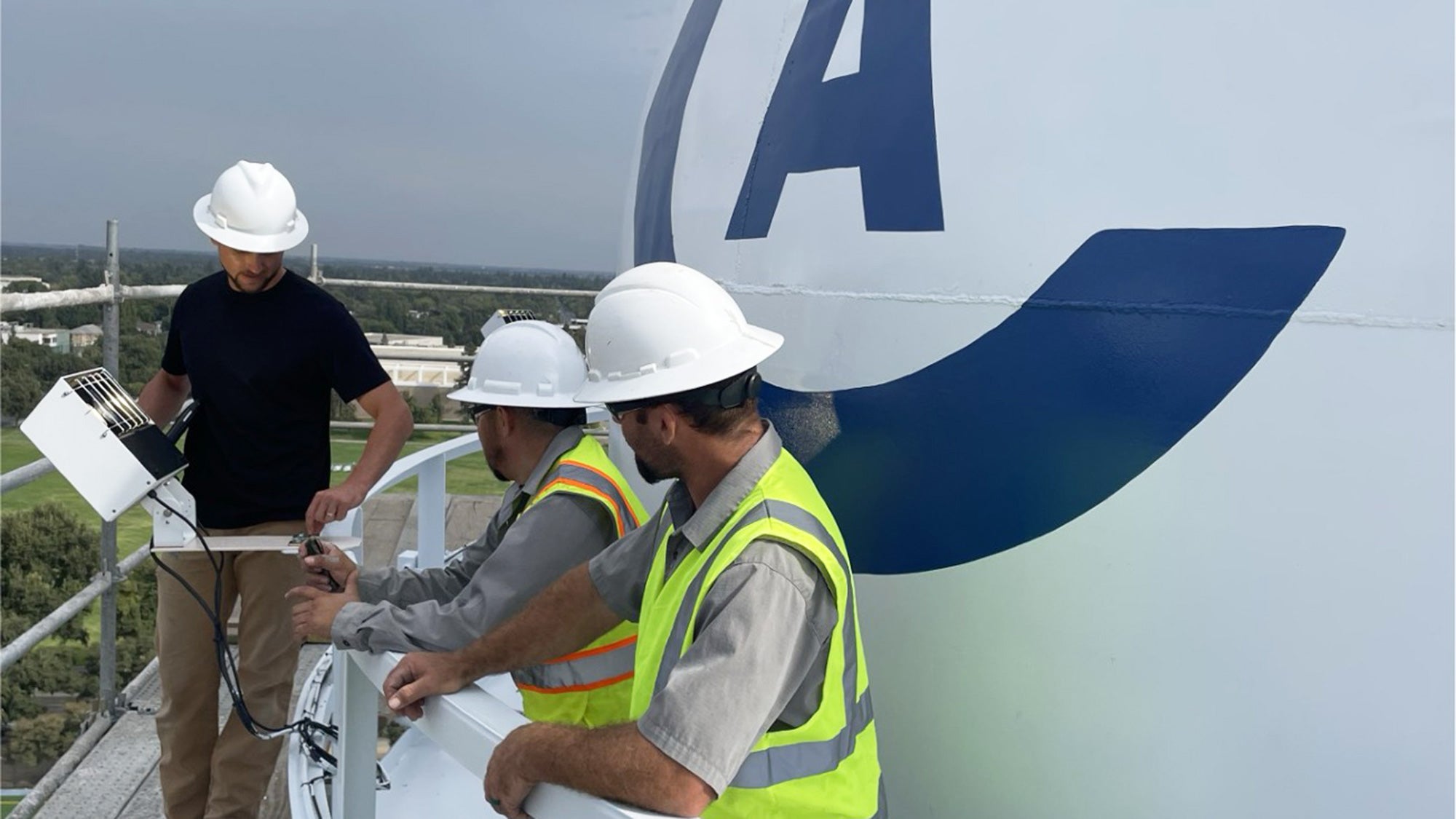 Workers install lights at the top of the tower