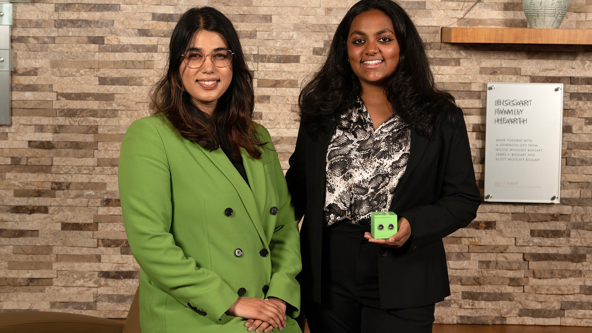 Two students one sitting one standing and holding a green box