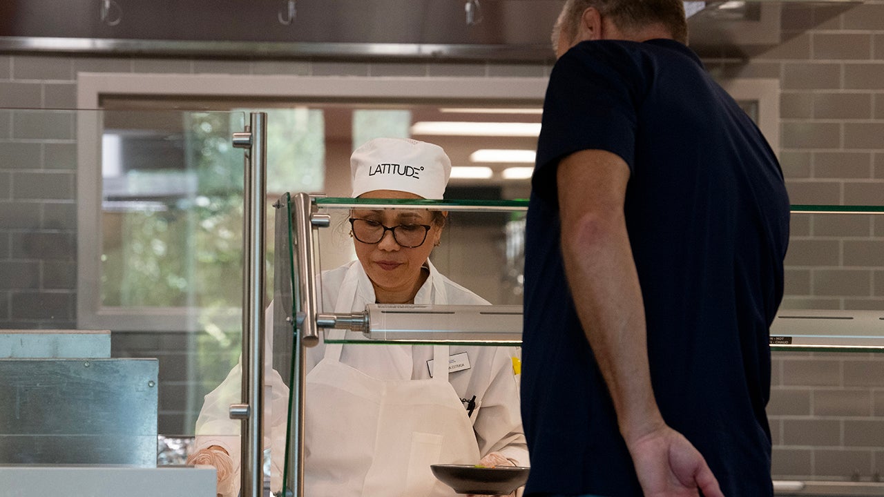 A woman behind a counter serves food to a guest