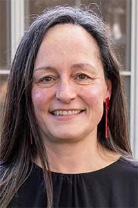 Smiling woman headshot with long dark hair, red earrings, black top
