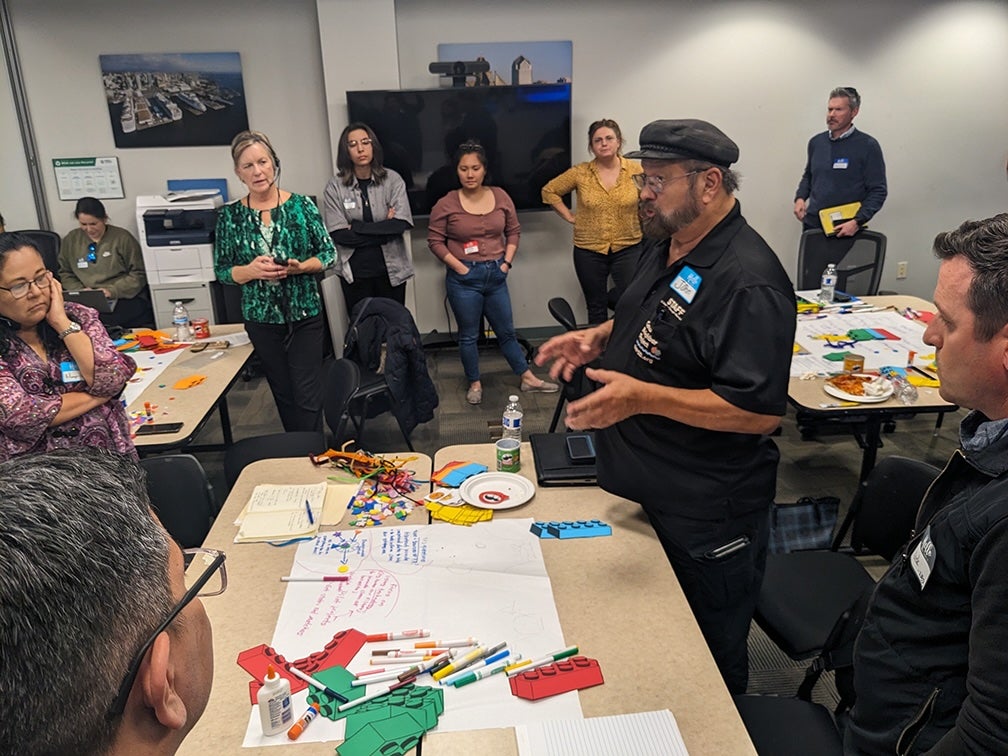 Community members stand around table at a Portside EJ Neighborhoods community meeting.