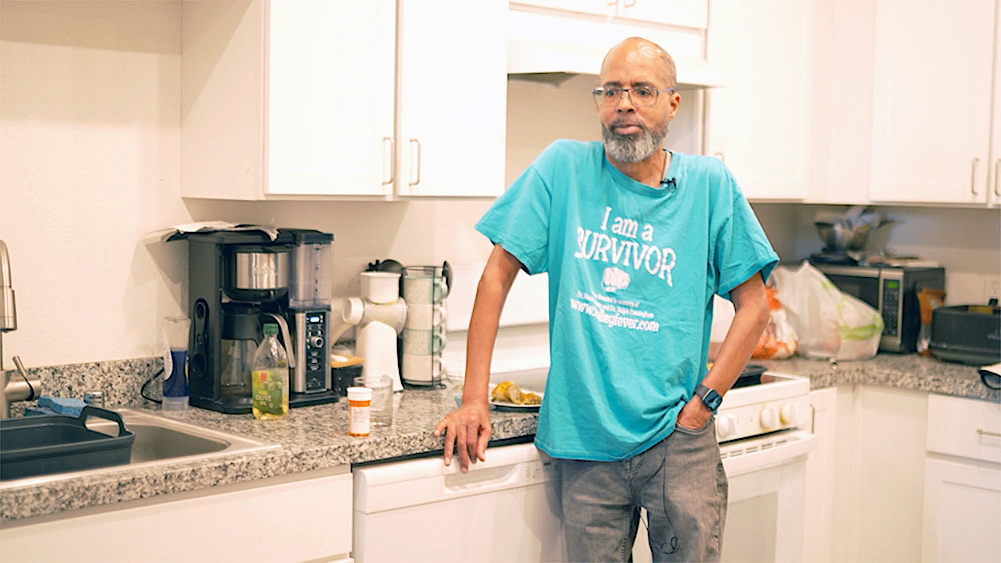 Man in kitchen wears an "I am a survivor" T-shirt