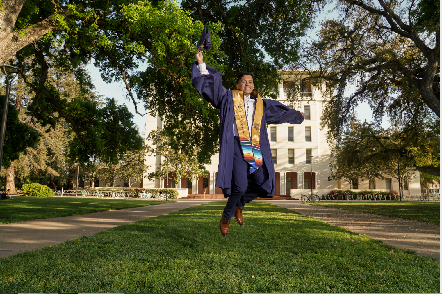 UC Davis grad jumps in front of Mrak Hall for a graduation picture