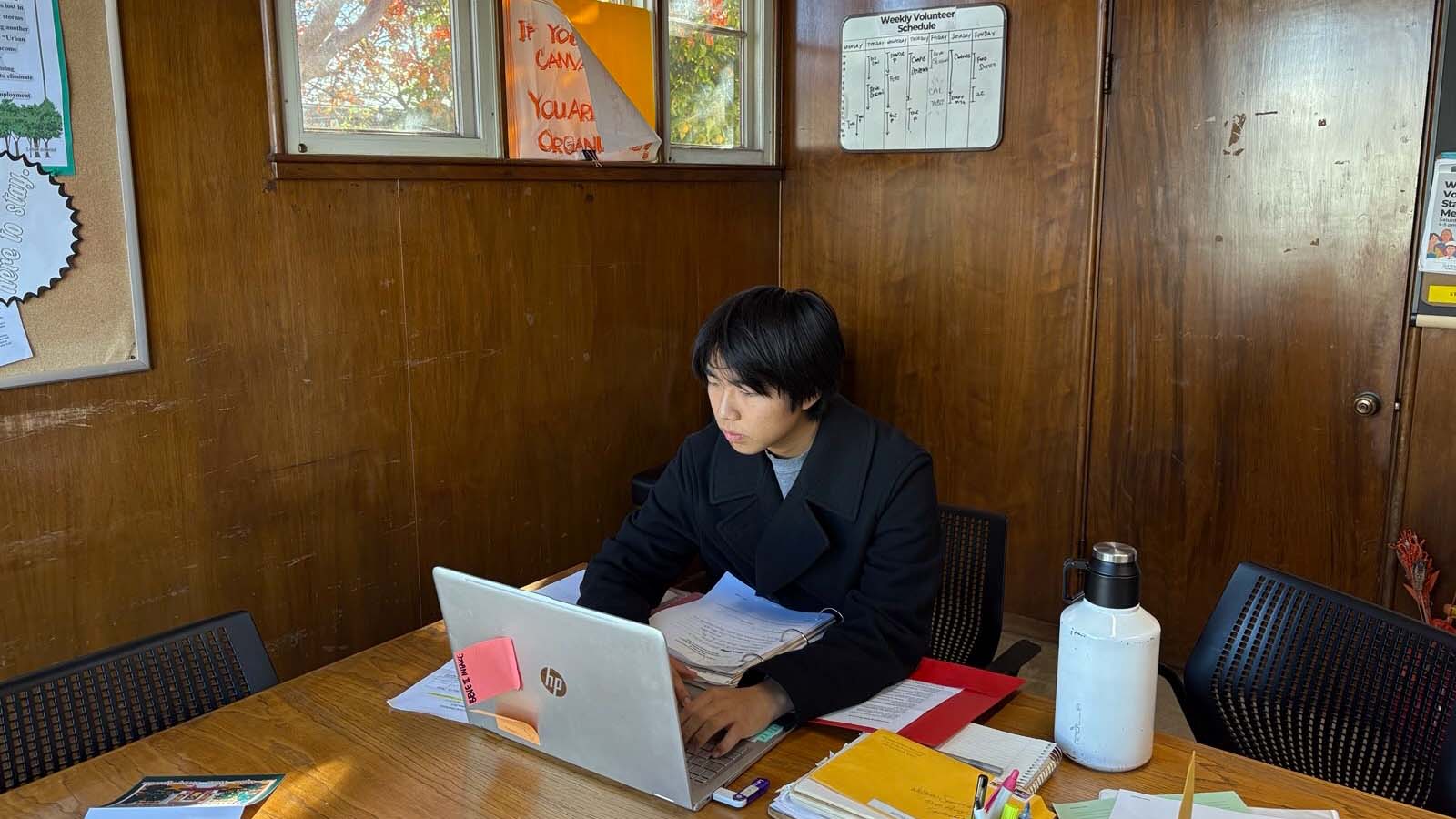 Seito Ezawa sits at table and uses laptop
