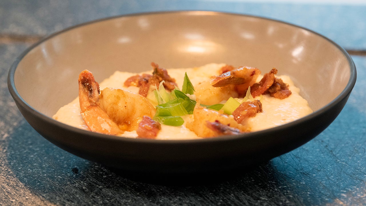 A bowl of Cajun-spiced shrimp over grits with bacon, green onions and chili oil.
