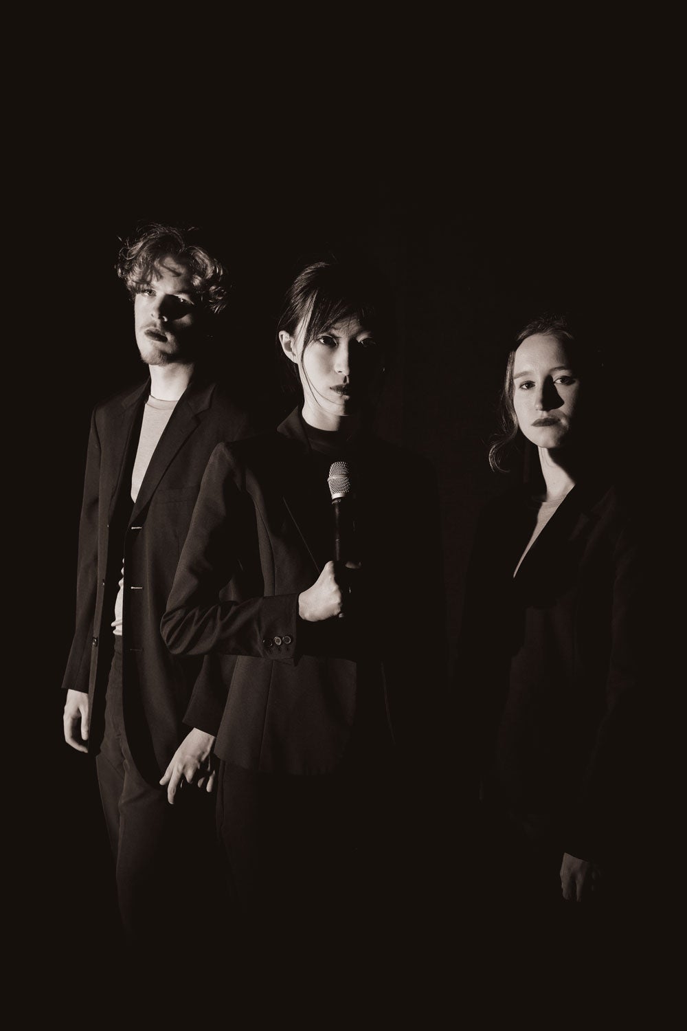 Three actors on stage all dressed in black 