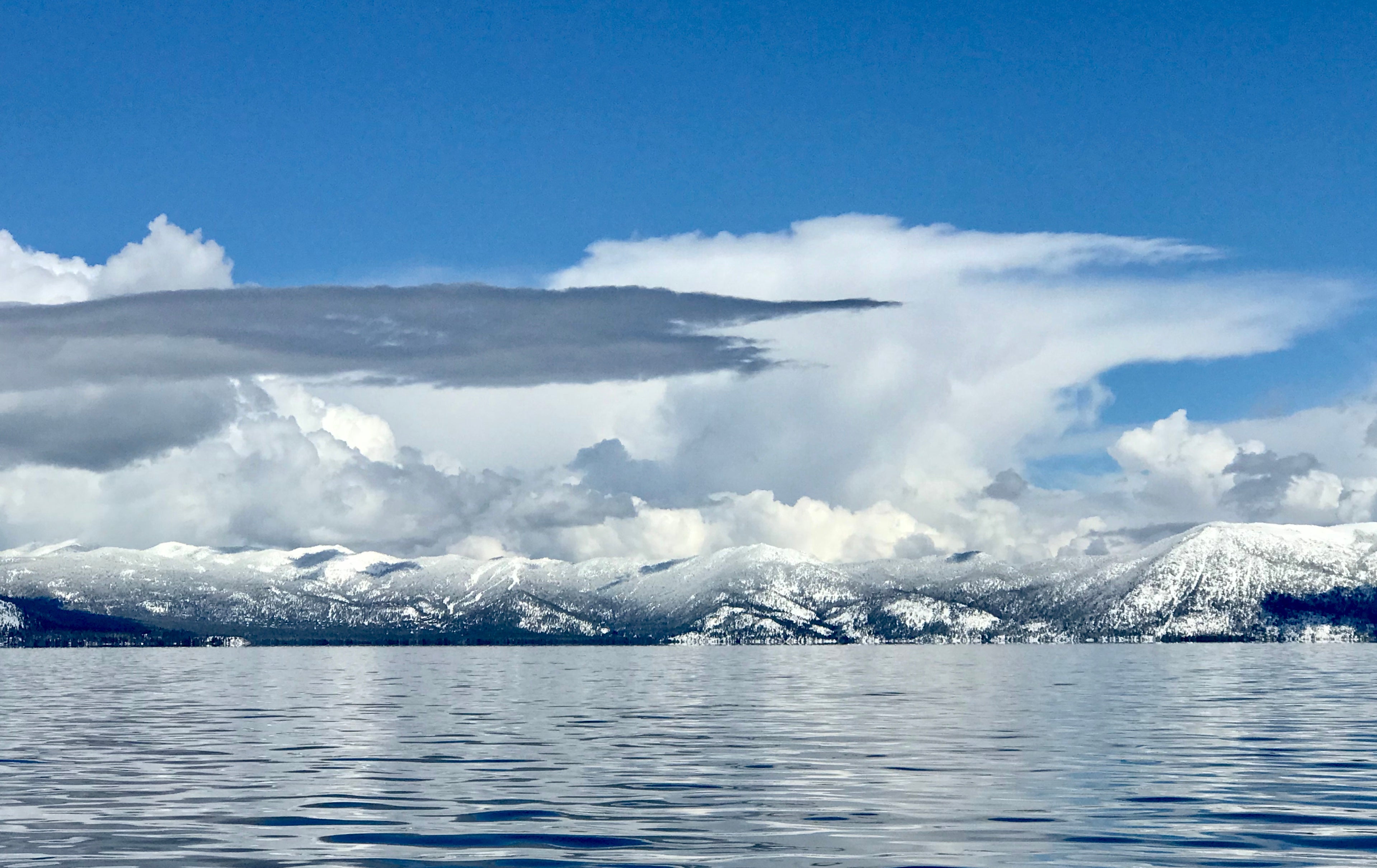 Lake Tahoe with snow-capped mountains in background under winter clouds