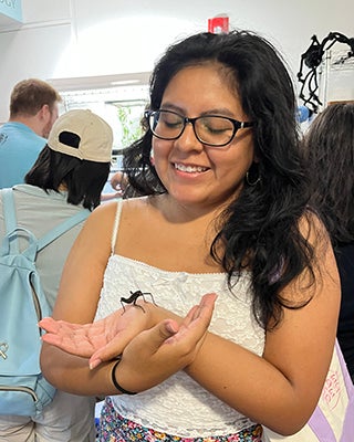 Teresa Huancas Flores looks down at a bug in her hands