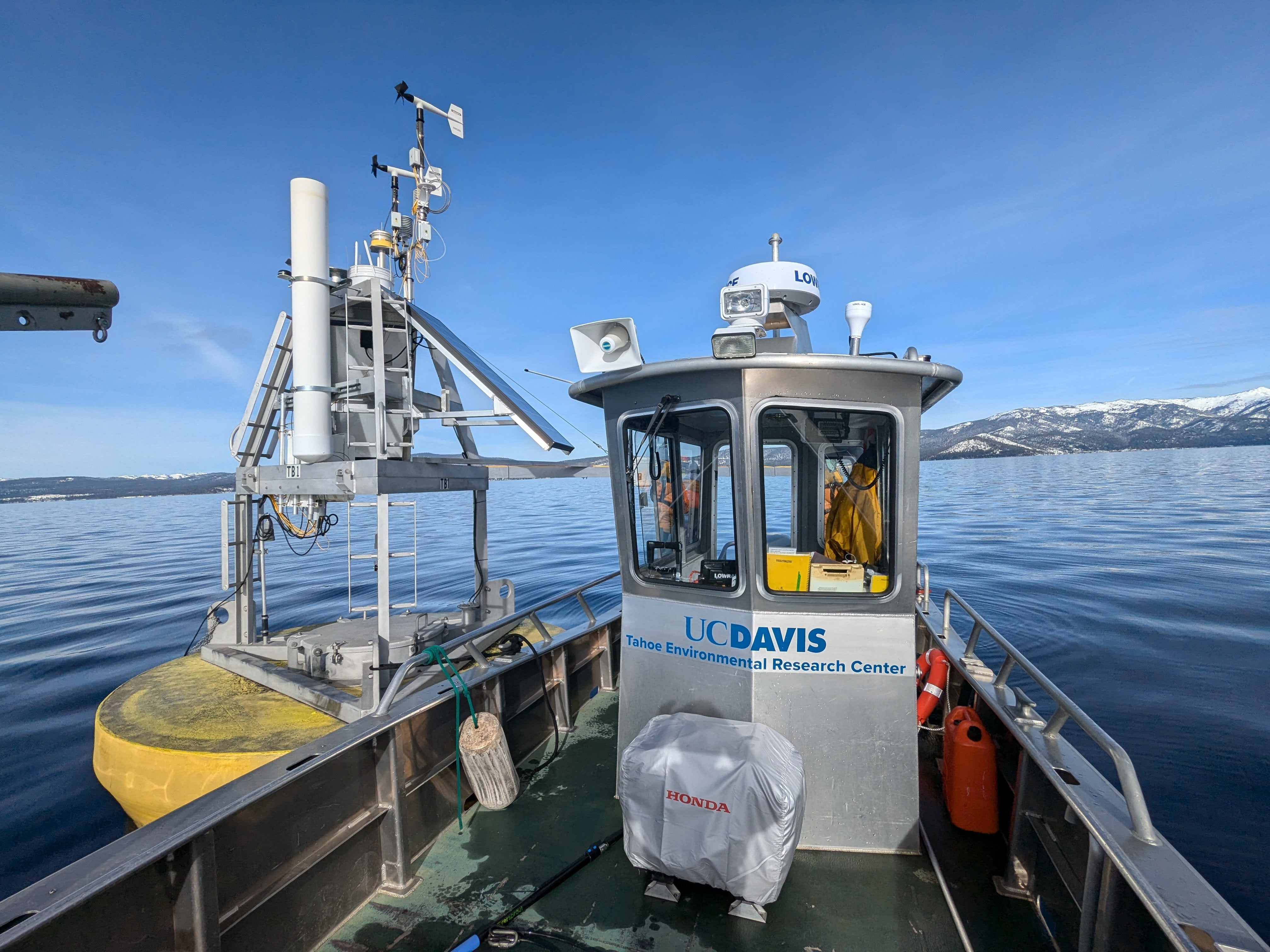 A research vessel labeled with UC Davis Tahoe Environmental Research Center floats next to a NASA buoy at Lake Tahoe
