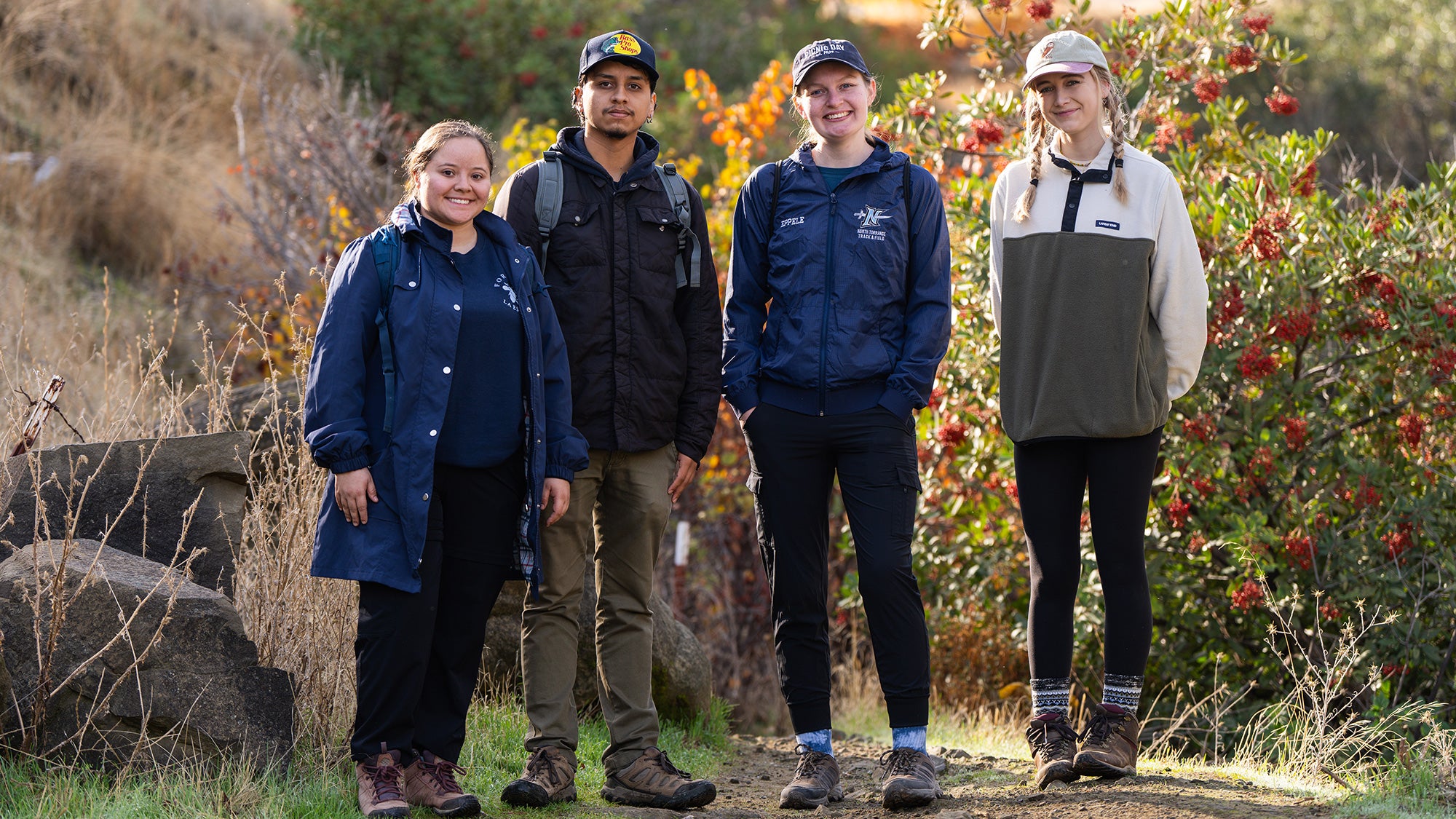 Four college students stand for the camera on a hiking trail