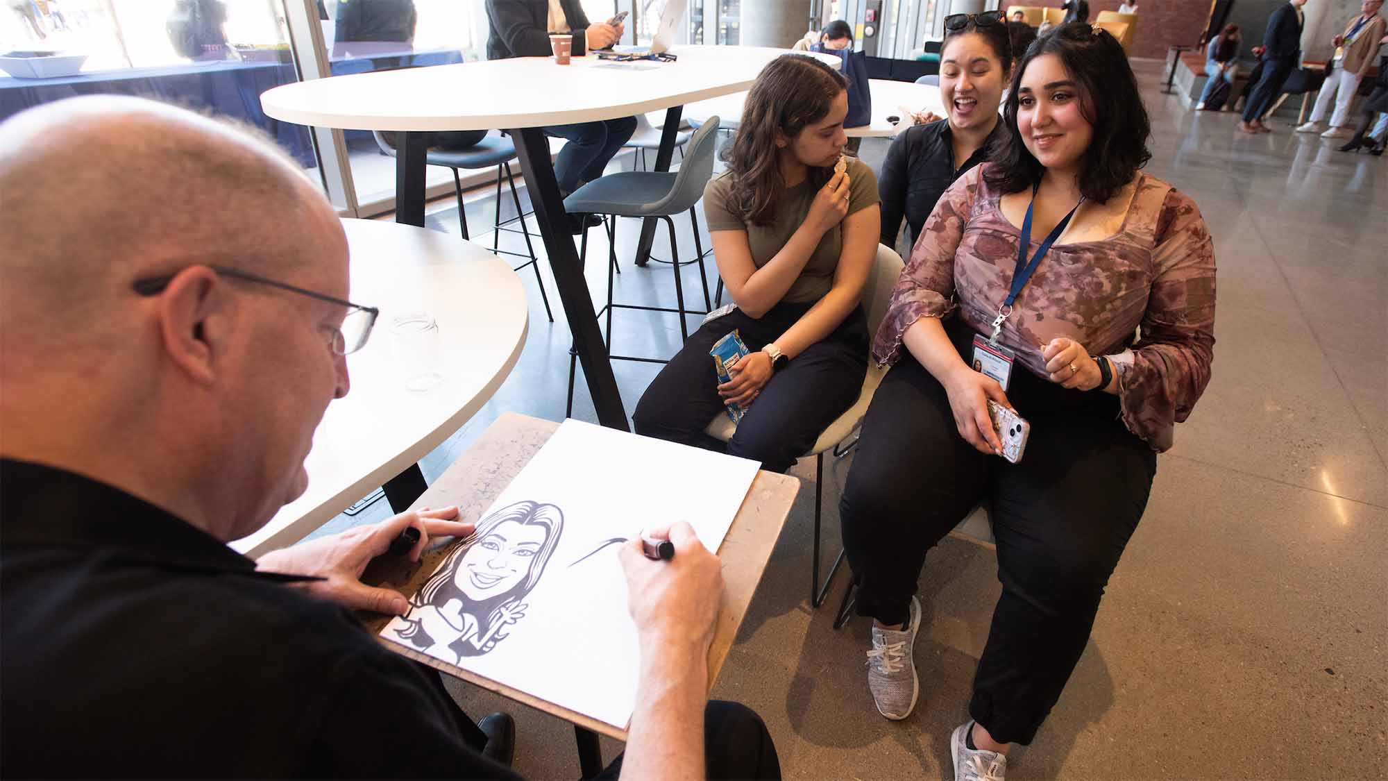 Three people sit for caricature drawing