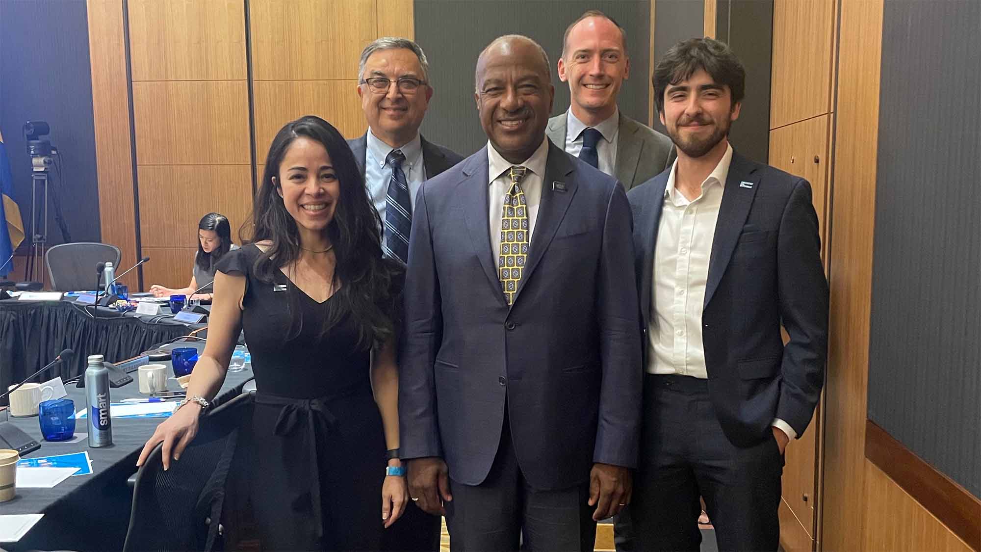 Four people pose for photo at Regents meeting