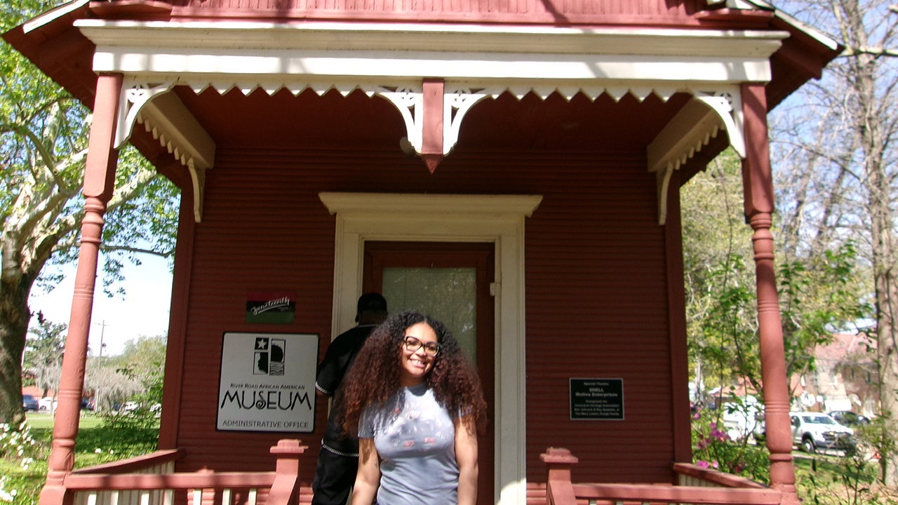 Natasha Bibbs stands on the steps of a small red building
