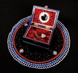 A decorative box with red interior, surrounded by a colorful circular design on a black background.