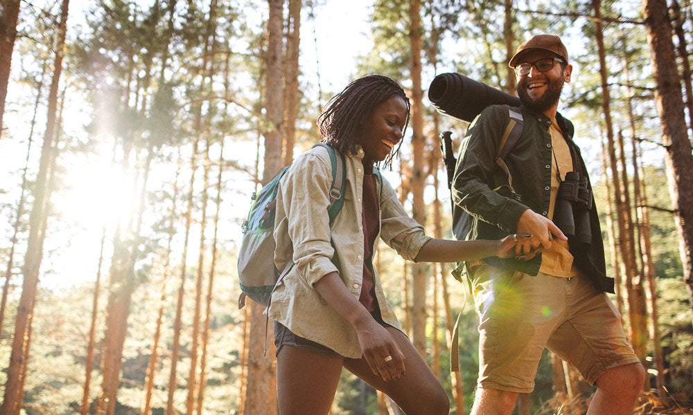 Two people hike though a redwood forest