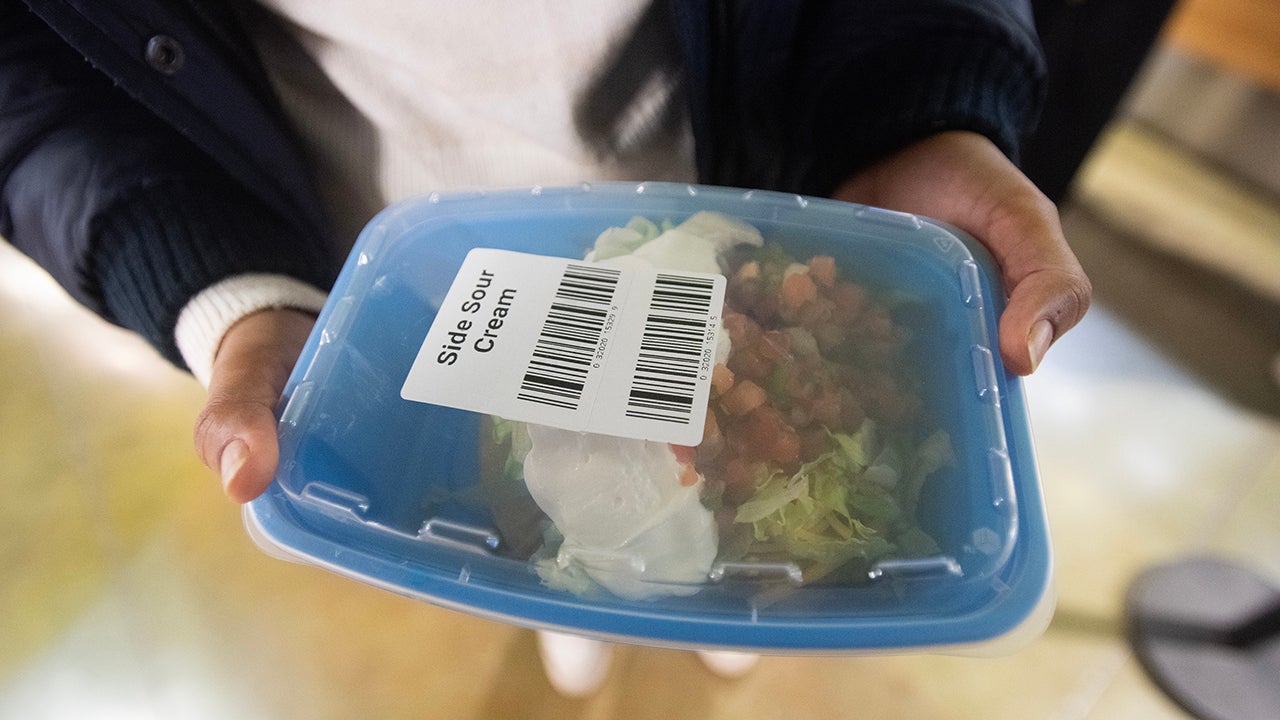 A closeup of a blue, reusable container with food in it and a transparent lid on it.