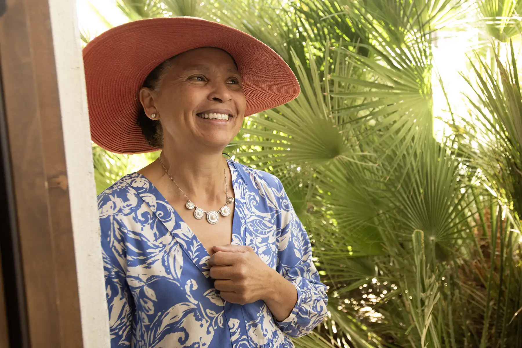 Portrait of a woman leaning against a door jamb and looking off camera, smiling.