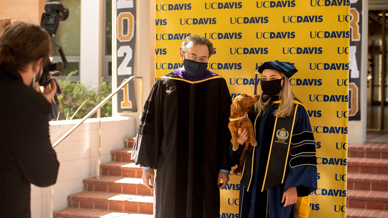Dean Kevin Johnson poses for photo with student and dog.
