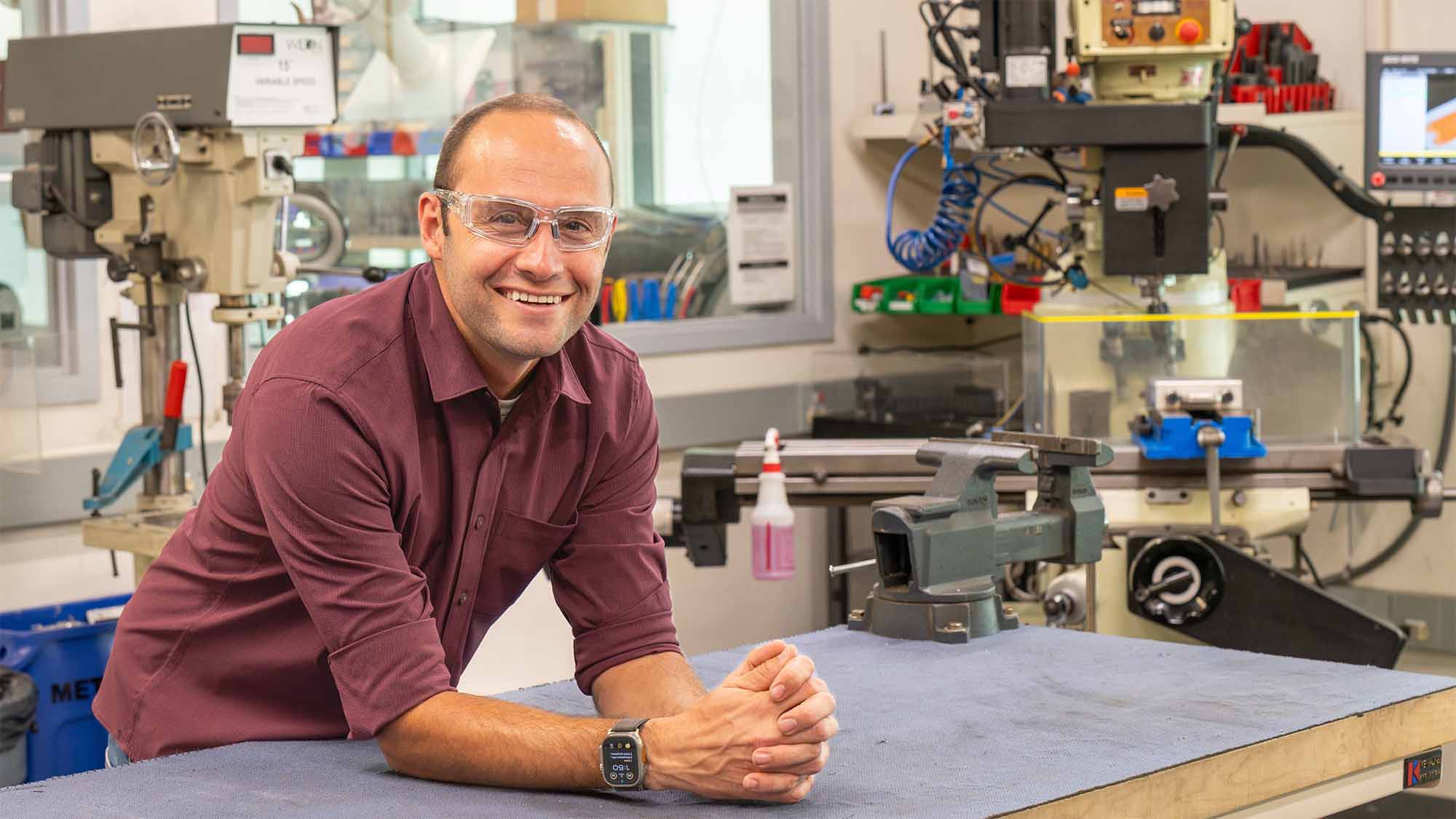 Steven Lucero posing for photo in lab with lots of machinery.