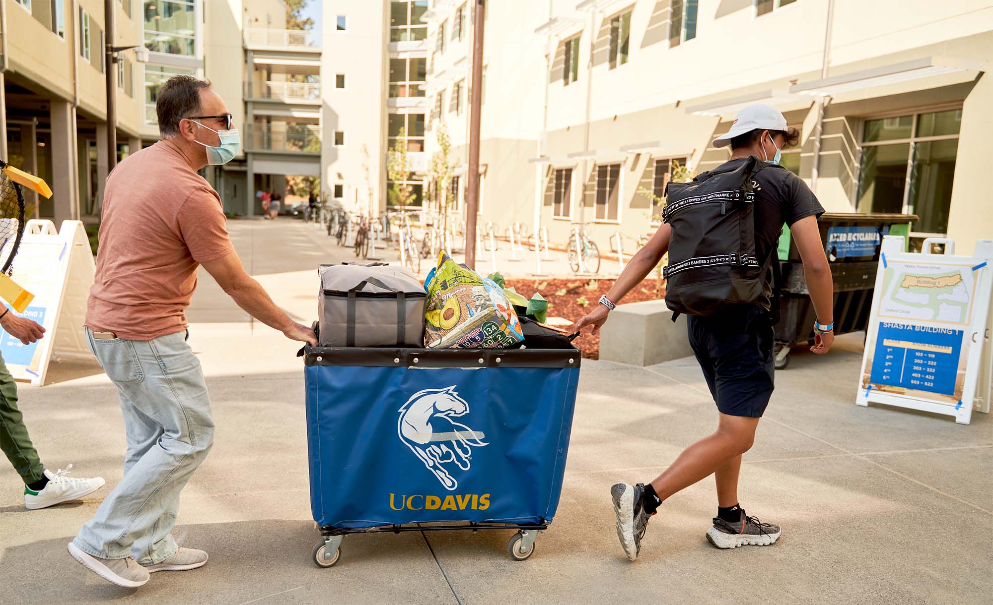 Student and father push moving cart outside Shasta Hall.