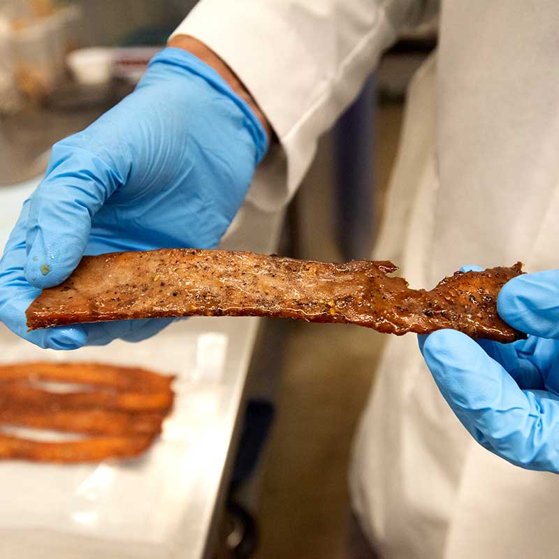 Closeup photo of blue-gloved hands holding fish meat.